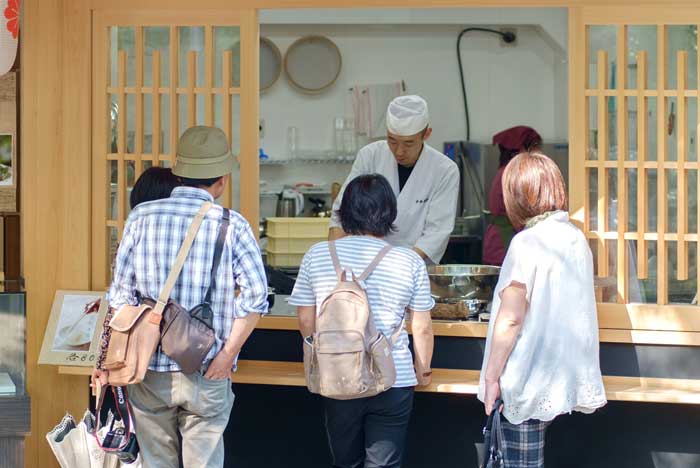 店頭で葛菓子を作りお客様に説明する店主